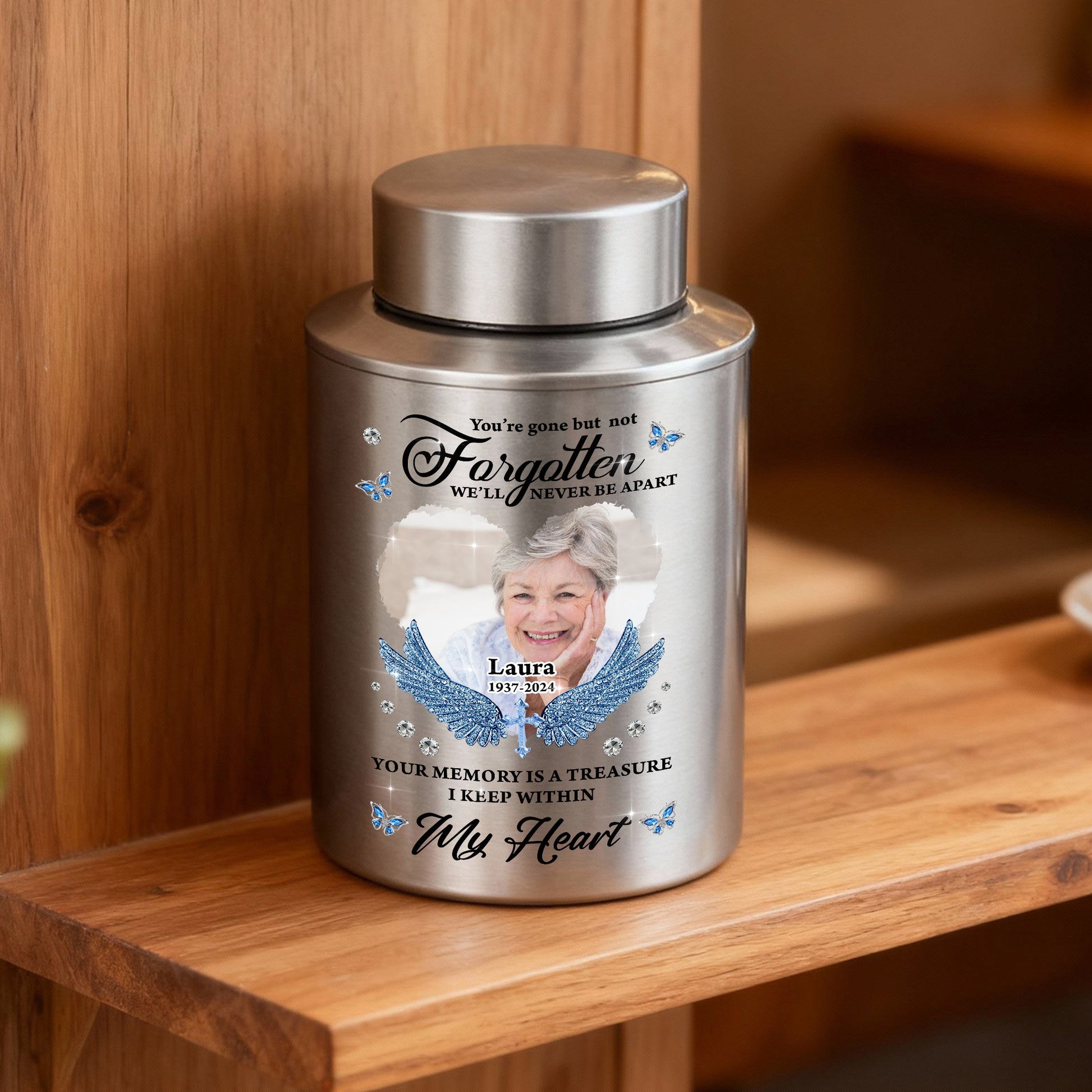 Stainless steel keepsake urn for ashes with "In Loving Memories" engraving, displayed on a dark surface.