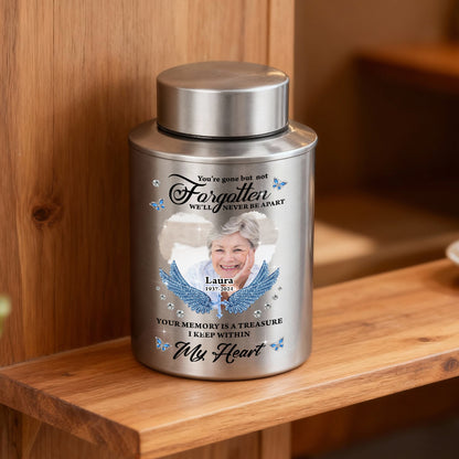 Stainless steel keepsake urn for ashes with "In Loving Memories" engraving, displayed on a dark surface.