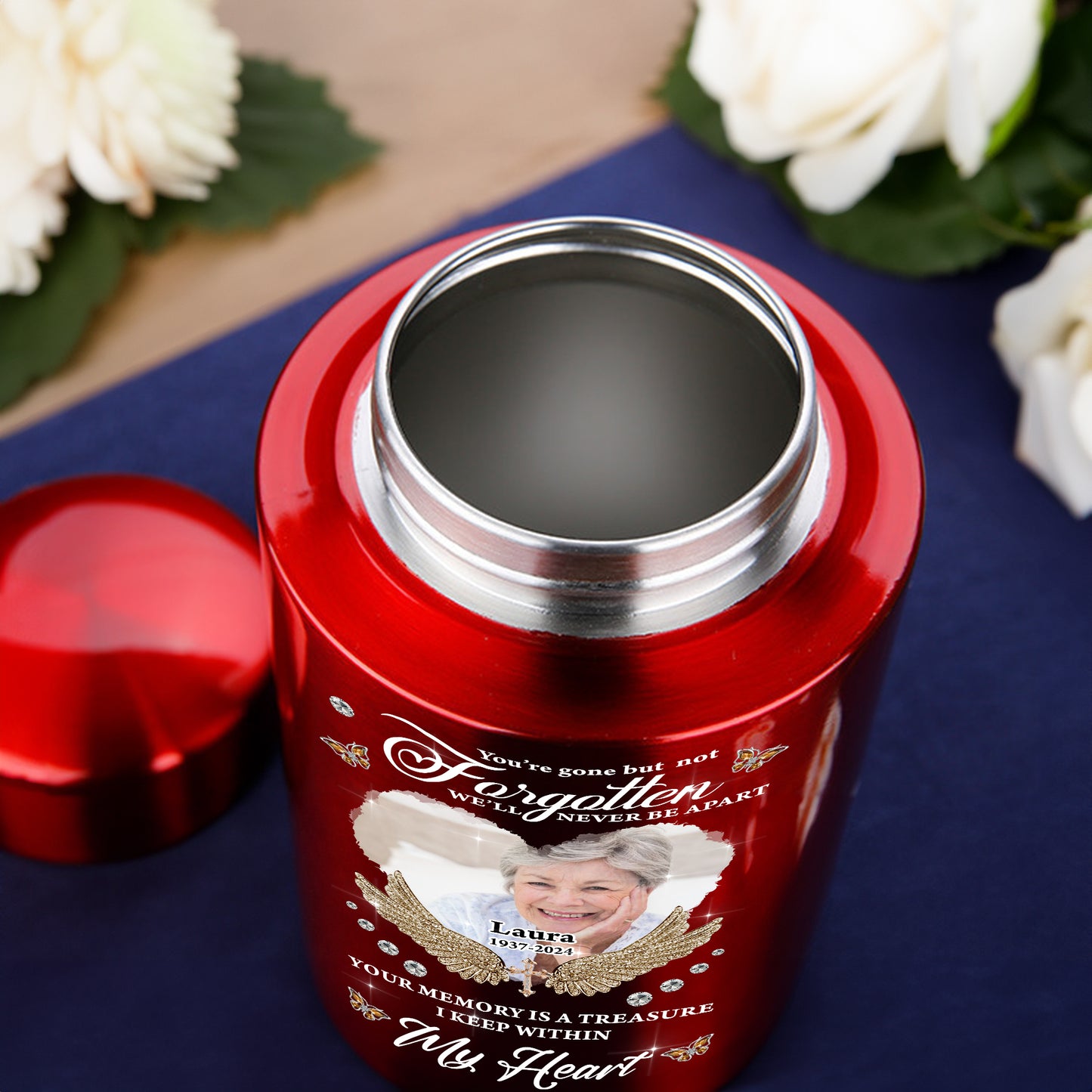 Stainless steel keepsake urn for ashes with "In Loving Memories" engraving, displayed on a dark surface.